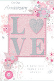 This anniversary card is a gentle tribute to enduring romance, designed with the soft elegance you often see in Mayfair's quieter side streets. The background is a wash of pastel blush pink and silvery grey, creating a calm, intimate mood. At the centre, the word LOVE is spelled out in raised glitter, each letter smooth and slightly rounded, with the O replaced by a shimmering heart textured in silver that appears almost metallic under the light. The finish is refined rather than flashy, reminiscent of delicate jewellery in a nearby Burlington Arcade window. Surrounding this heart-shaped focal point, watercolour-soft blooms in blush and mauve unfold with an airy, romantic feel. Their contours are defined by fine, flowing lines and accented with subtle shading, suggesting the care of a florist placing each flower in just the right spot for an anniversary bouquet. Tiny details-scattered petals, whimsical swirls, and small, almost translucent butterflies-give a sense of gentle movement, as if a light breeze had passed over the card. Above and below, phrases such as On Our Anniversary and I love you today and always are written in a delicate, flowing script that feels personal and heartfelt. The composition, with its muted tones and graceful flourishes, carries the quiet sense of occasion you might associate with sharing a private celebration after receiving a same-day flower delivery to a Mayfair townhouse or a tucked-away hotel near Park Lane.